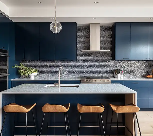 Keuken met donkerblauwe kasten, een kookeiland en barkrukken in een minimalistisch interieur.