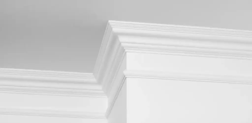 Witte plint in barokstijl op een witte muur.