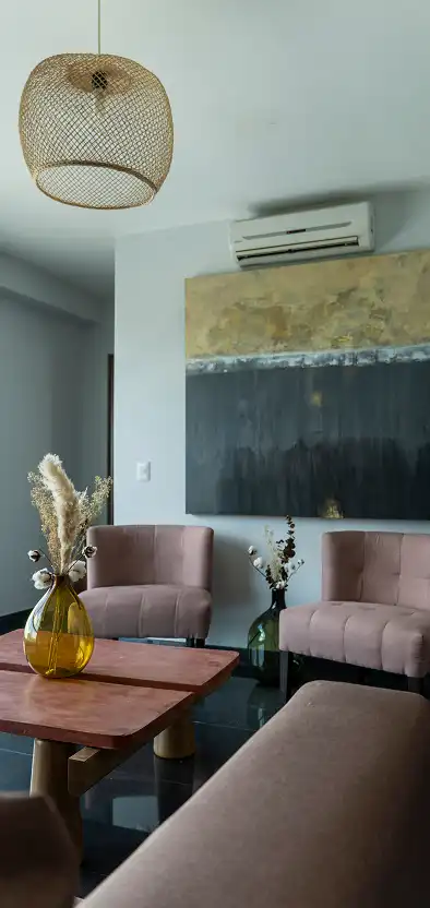 Klein deel van de woonkamer met fluwelen roze fauteuils en een abstract schilderij.